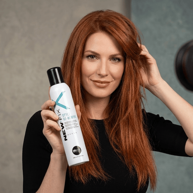 Woman with red hair holding a bottle of BBCOS New-Fix Dry Shampoo
