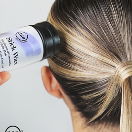 A close-up of a person's head from the back, showing dark brown to black hair with blonde highlights, while a hand holds a bottle of 360 Stick Nax Hair Color Primer against the hair. The 360 Stick Nax logo is visible on the bottle and as an overlay in the bottom-left corner.